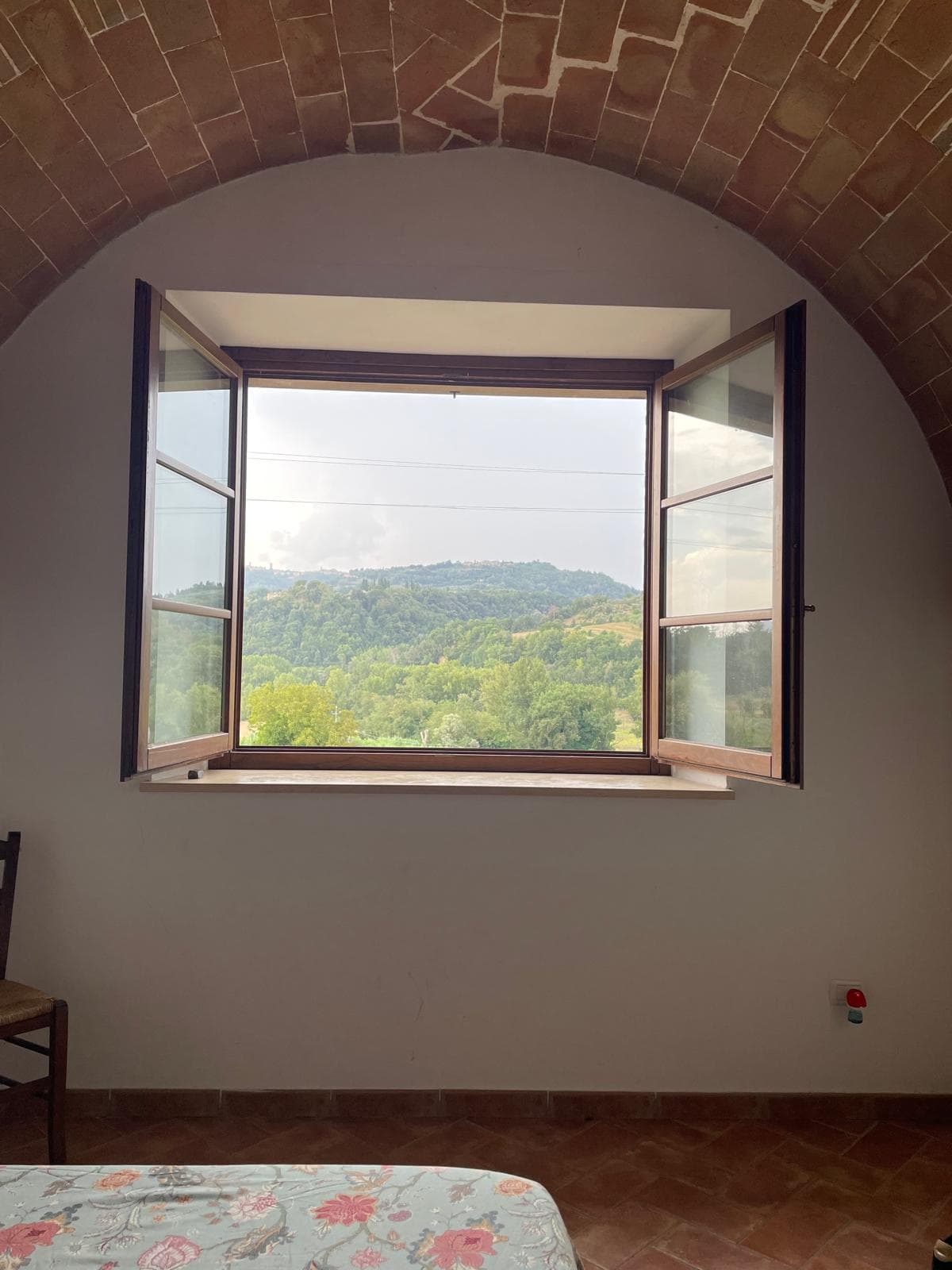 Arched brick-vault window opening to the Tuscan hillside