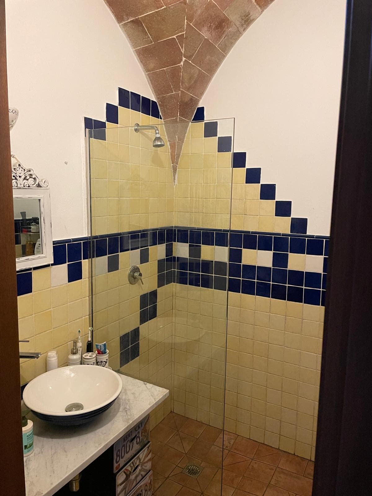 Cobalt and cream tiled shower under a brick-vault ceiling