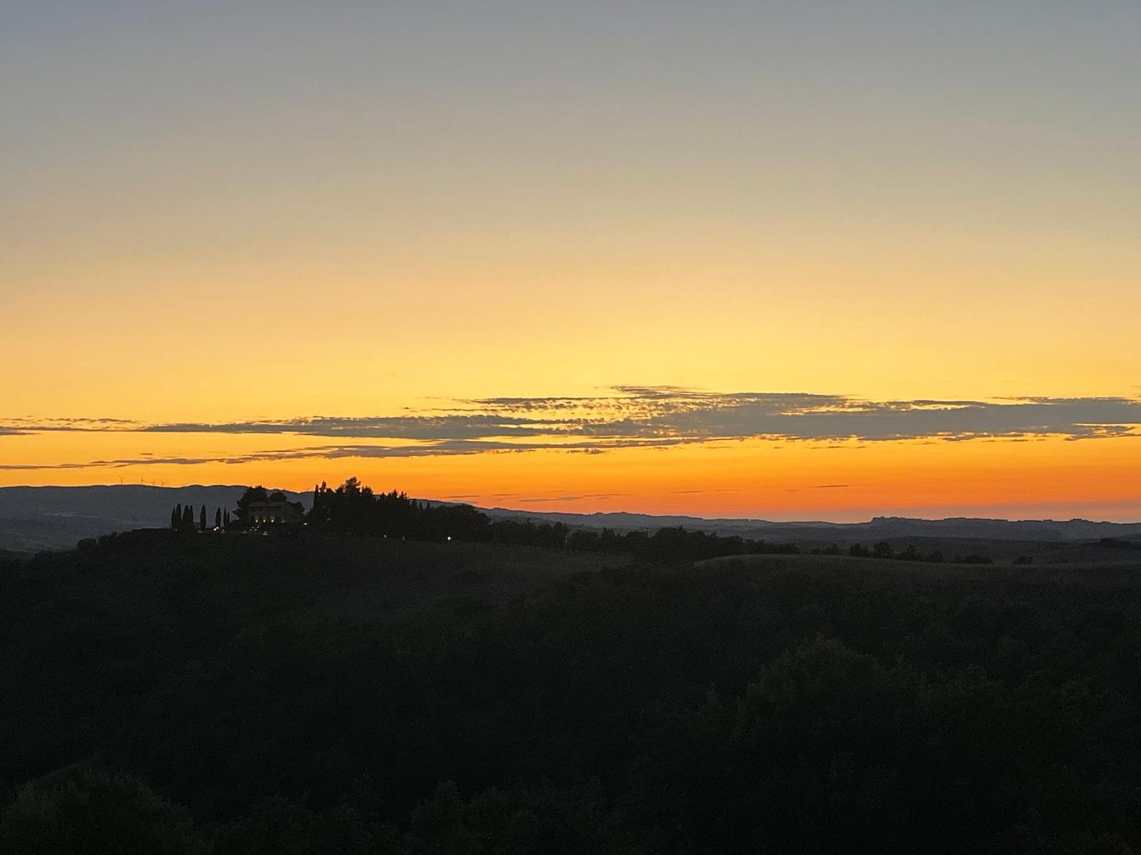 Tuscan countryside at golden sunset with cypress silhouettes