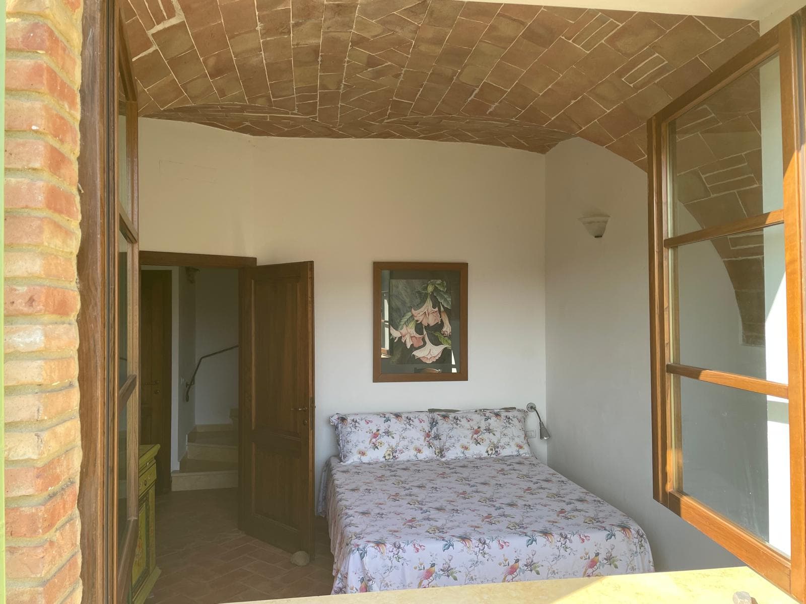 Double bedroom framed by a brick barrel vault and terrace door