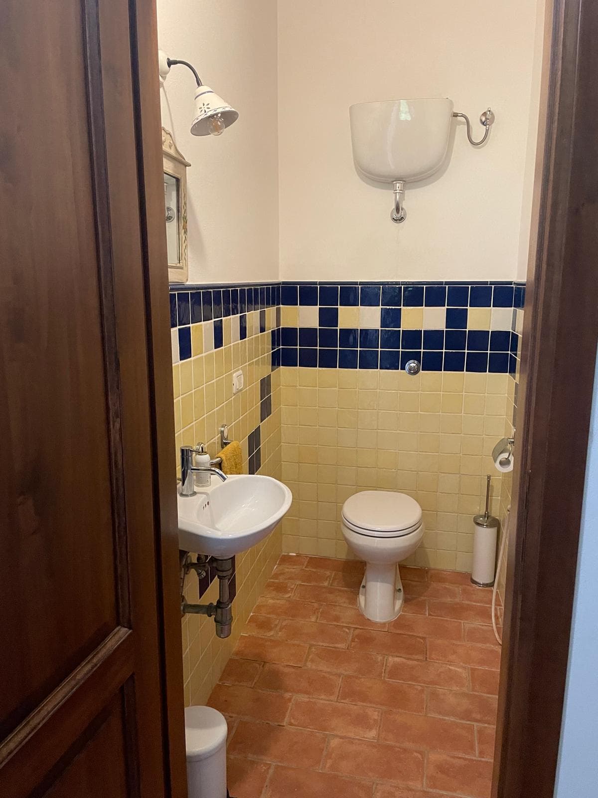 Powder room with yellow and cobalt tiles and a high cistern