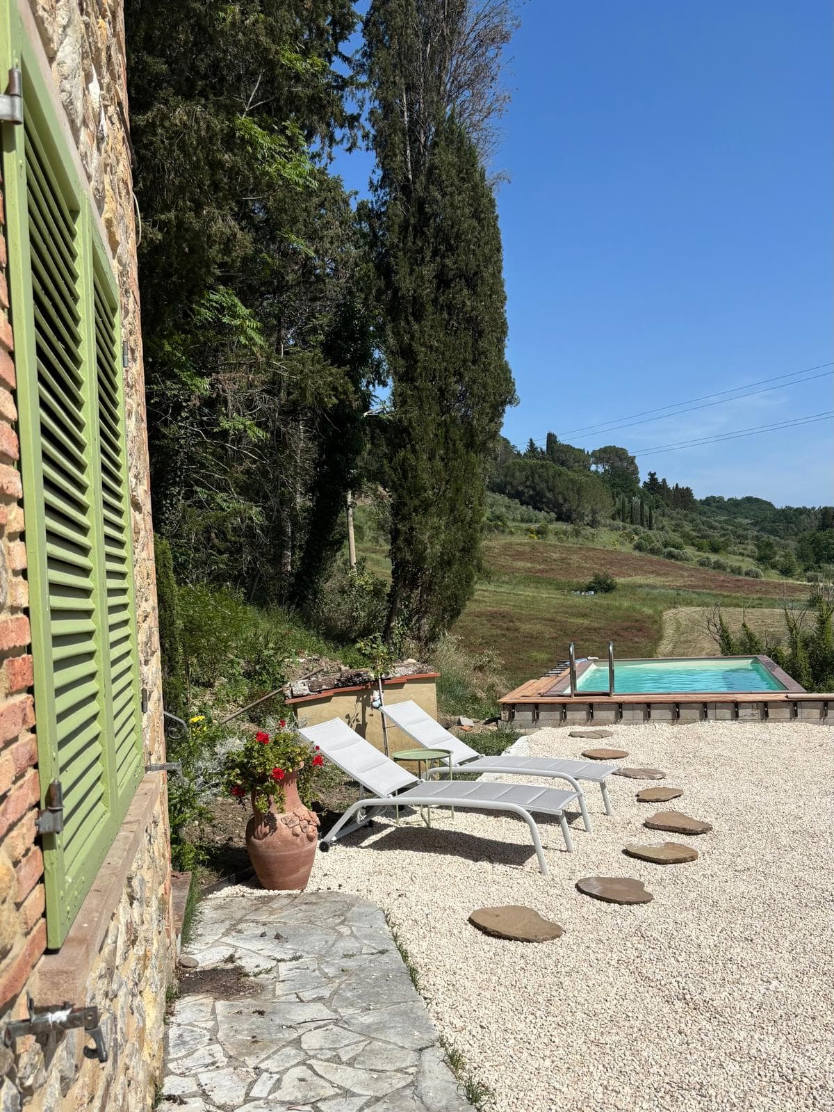 Sun loungers beside the pool with cypress and valley views