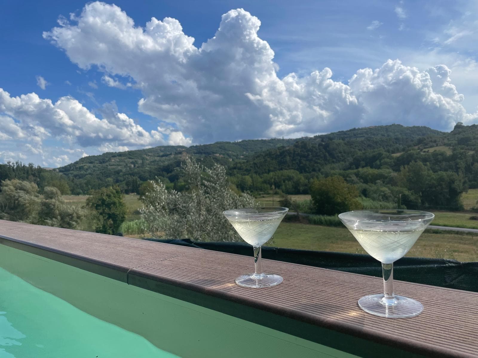 Champagne coupes on the pool edge with Tuscan hills beyond