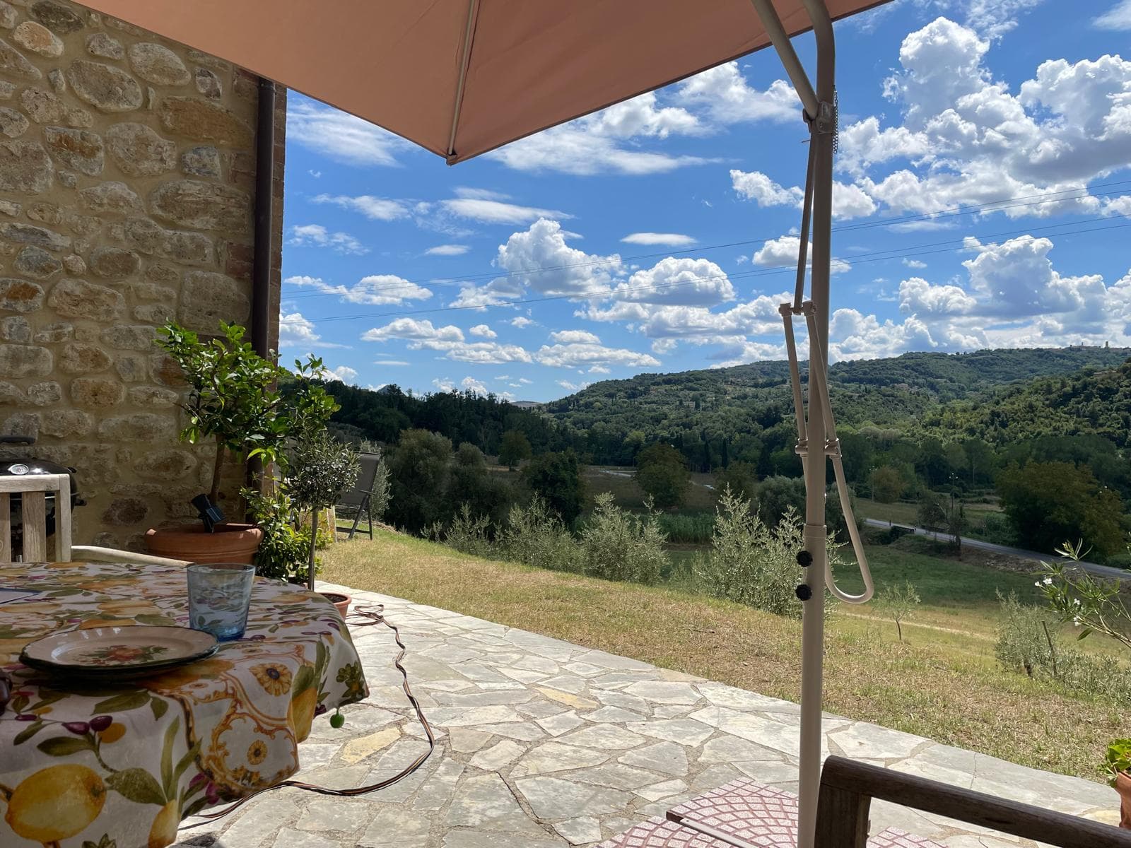 Stone terrace with a parasol table over the green valley